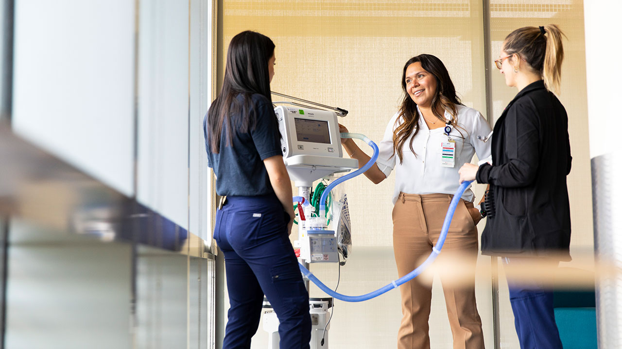 Three woman in a hospital setting have a conversation.