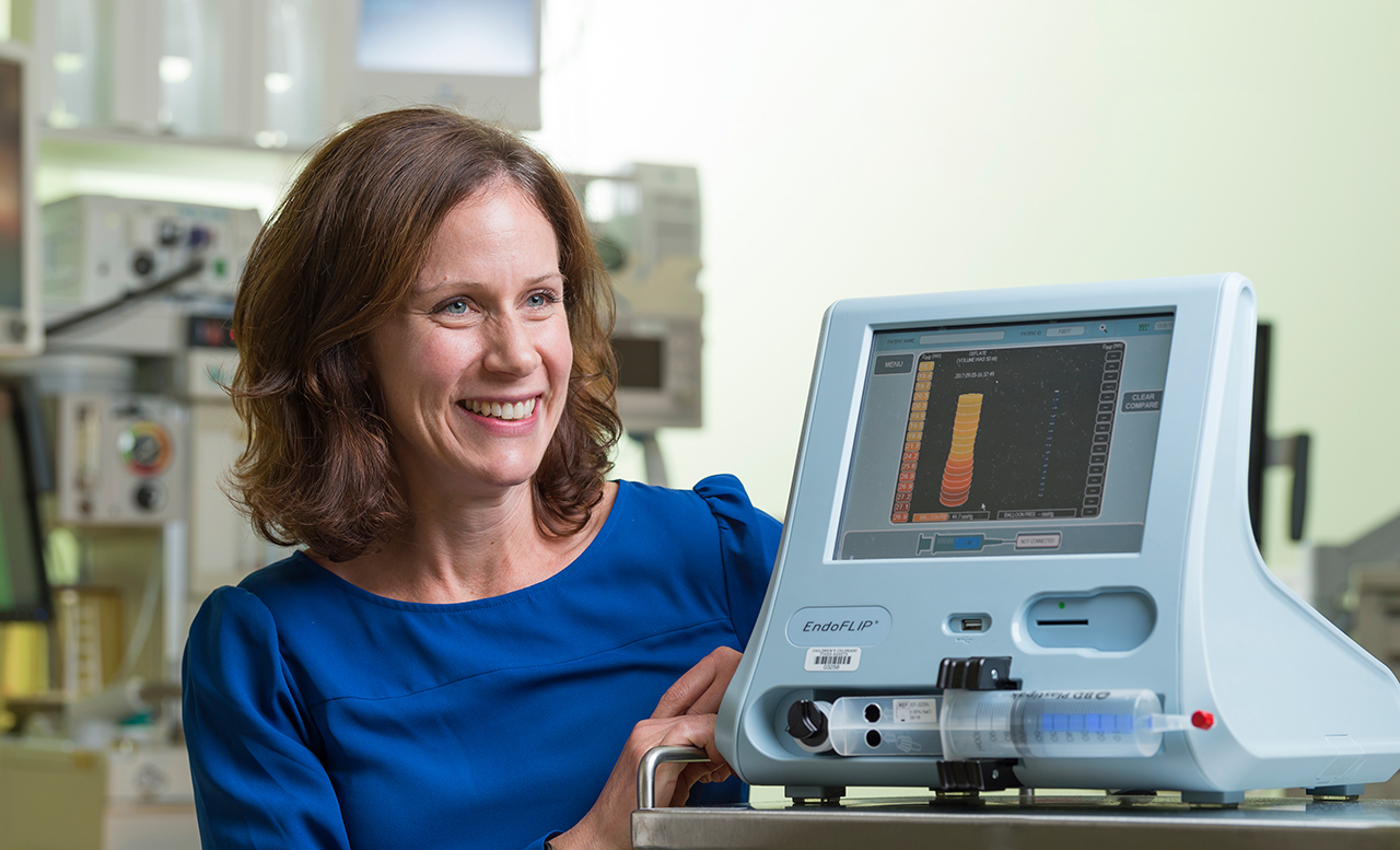 A woman in a blue shirt sits smiling at a EndoFLIP machine.