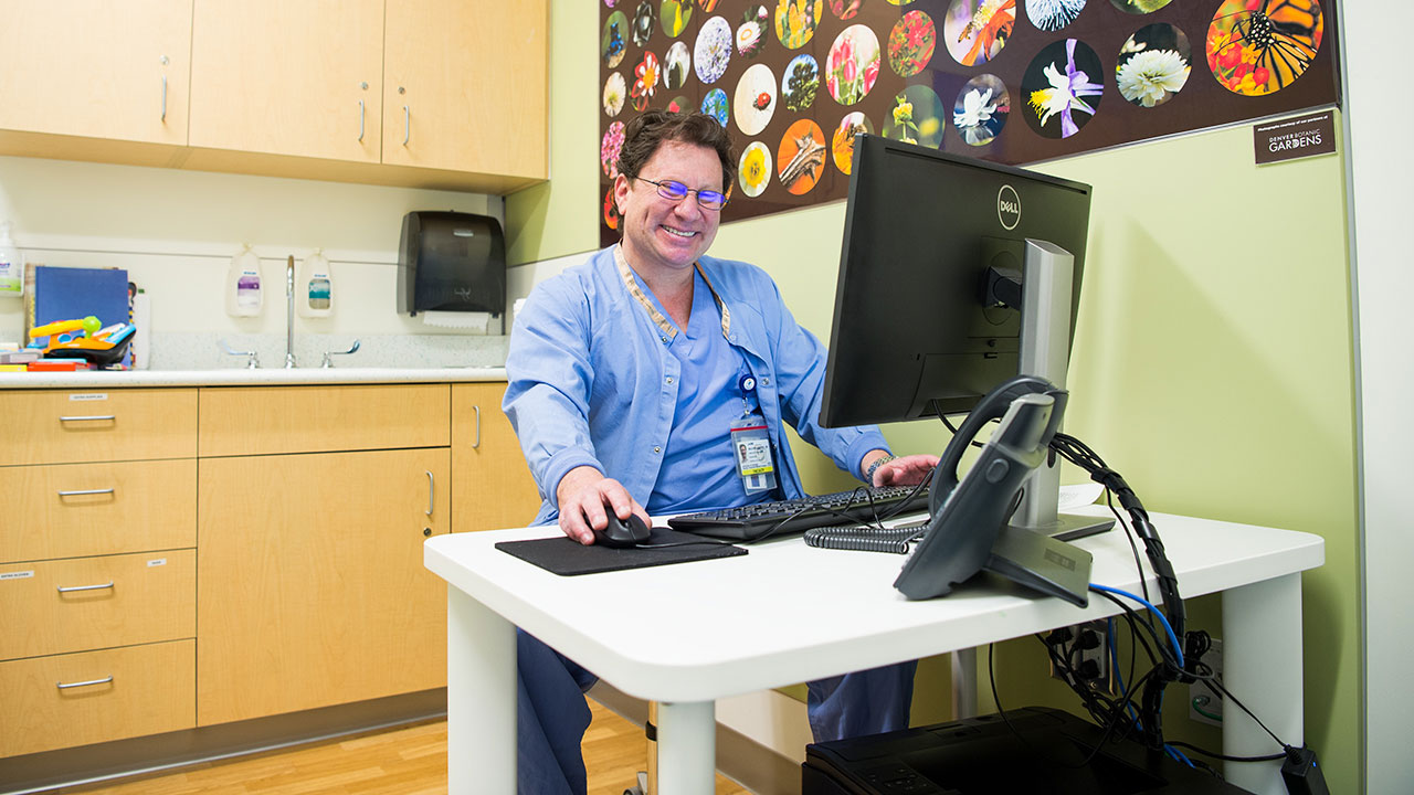 Dr. smiling and laughing while on the computer.