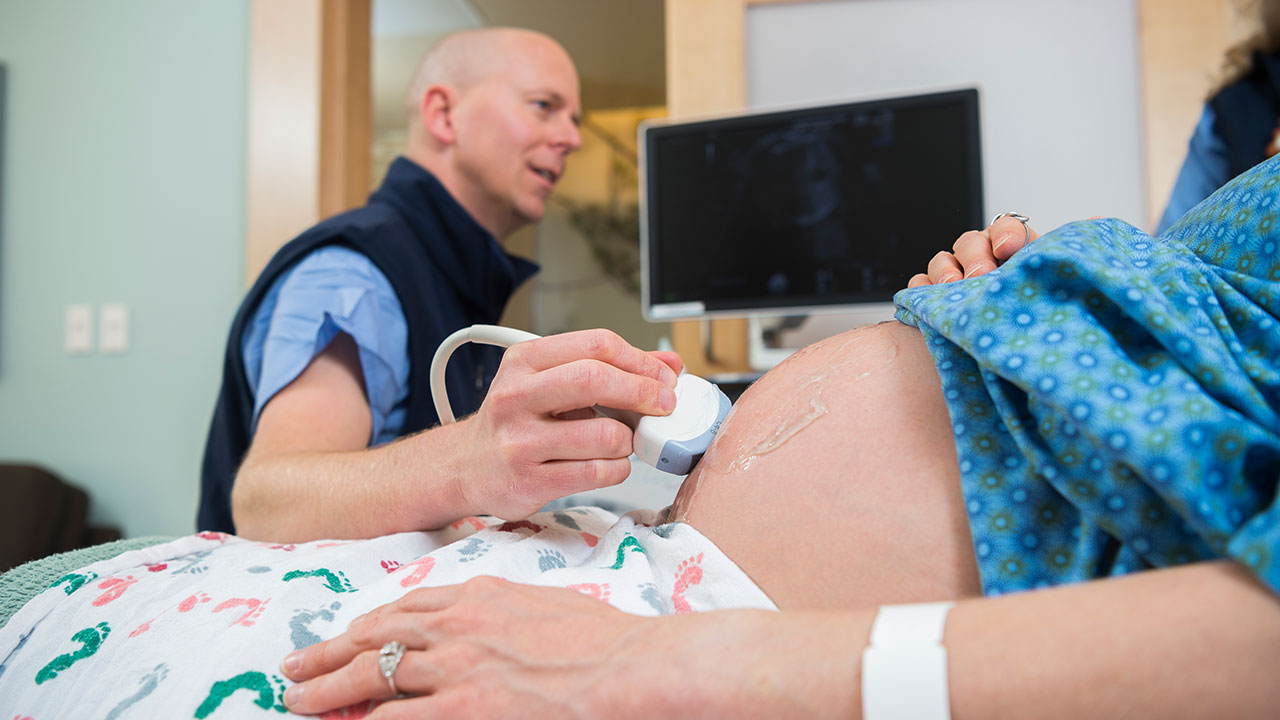 Provider performs an ultrasound on a pregnant woman.