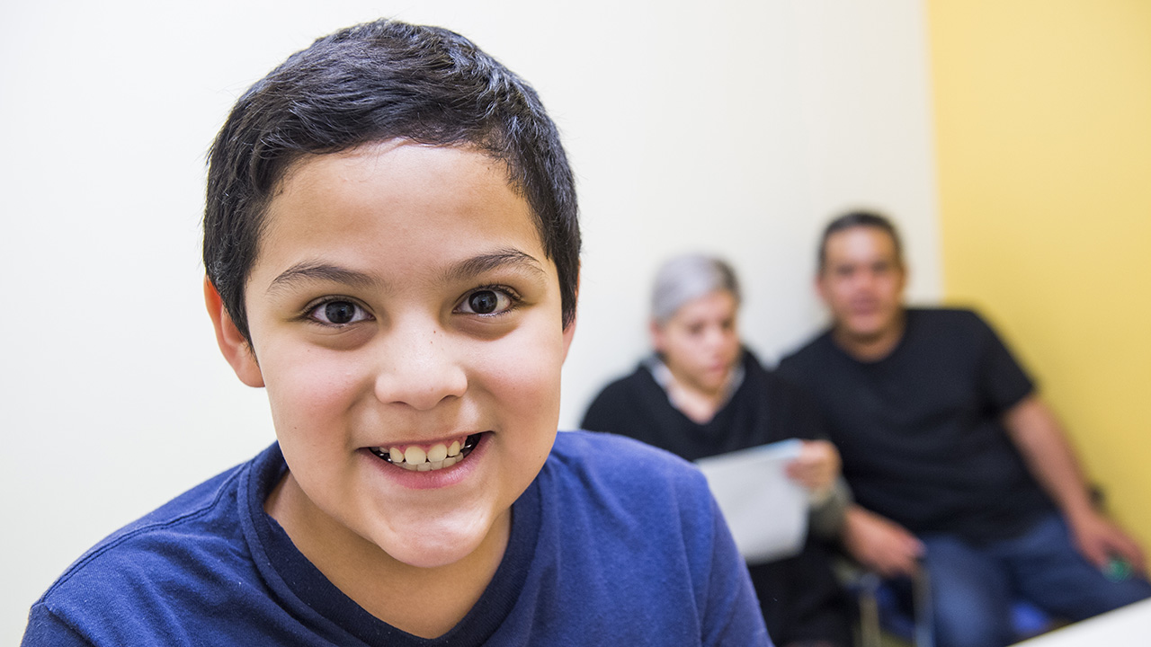 Smiling kid with parents in background