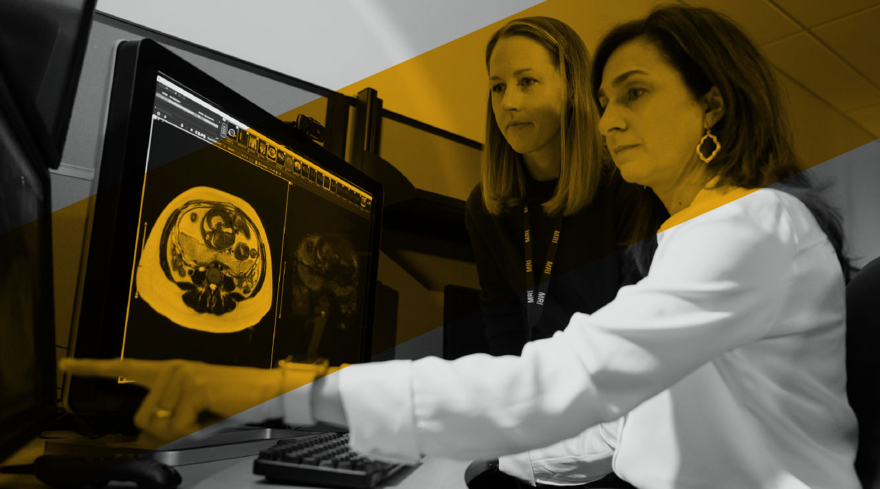 Two providers review an MRI scan on a computer screen together.