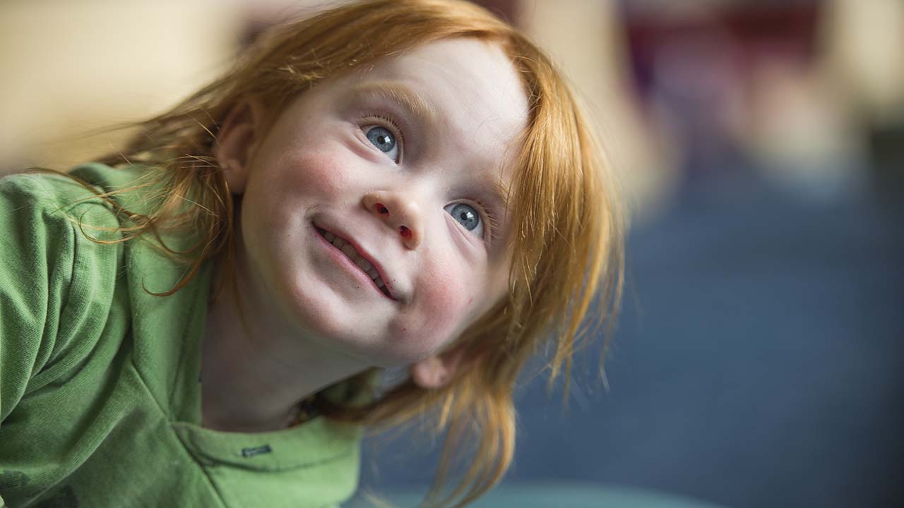 Young child smiling and looking up.