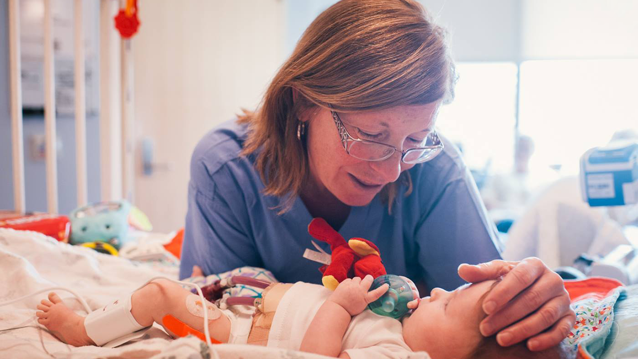 Provider in scrubs looking at baby in hospital bed